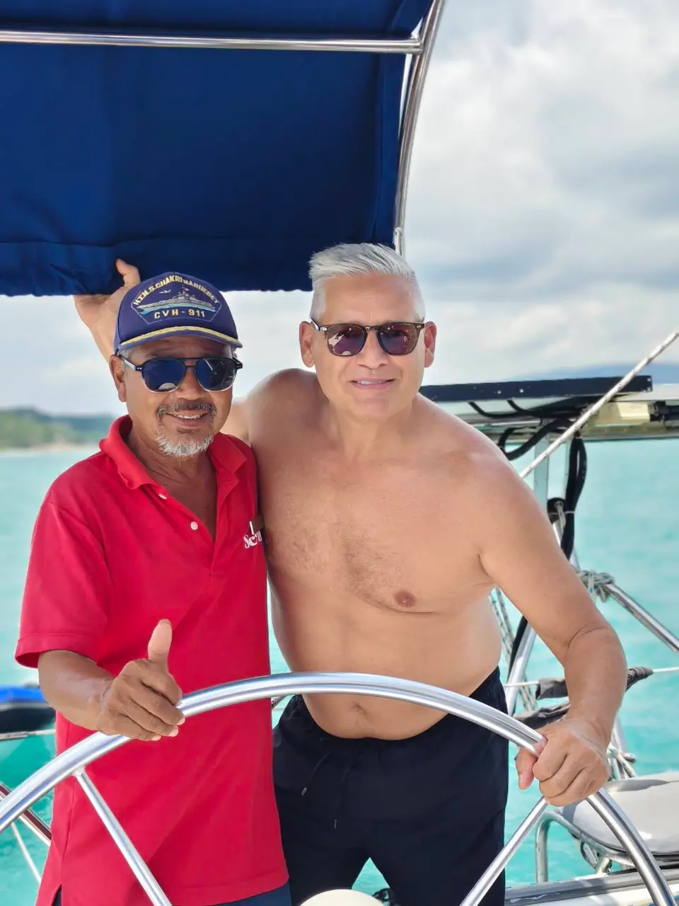 Our captain, in red, at the helm of a Samui Yacht Charters yacht with a guest