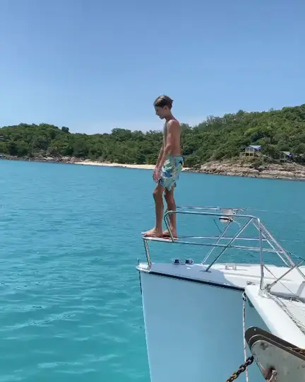 A boy diving off the bow into turquoise water