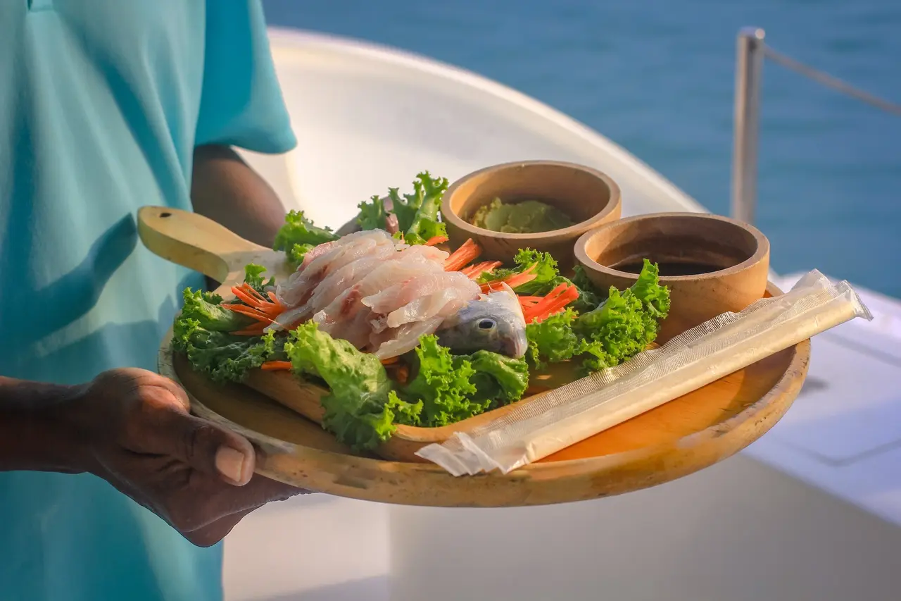 A crew member serving a Thai salad platter on deck