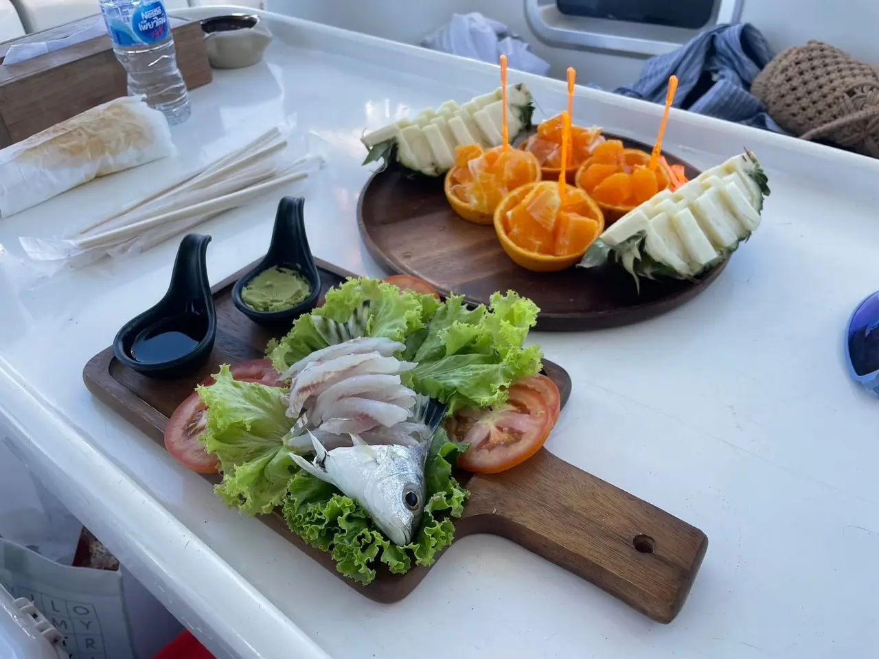 Fresh sashimi and fruit on a wooden board aboard