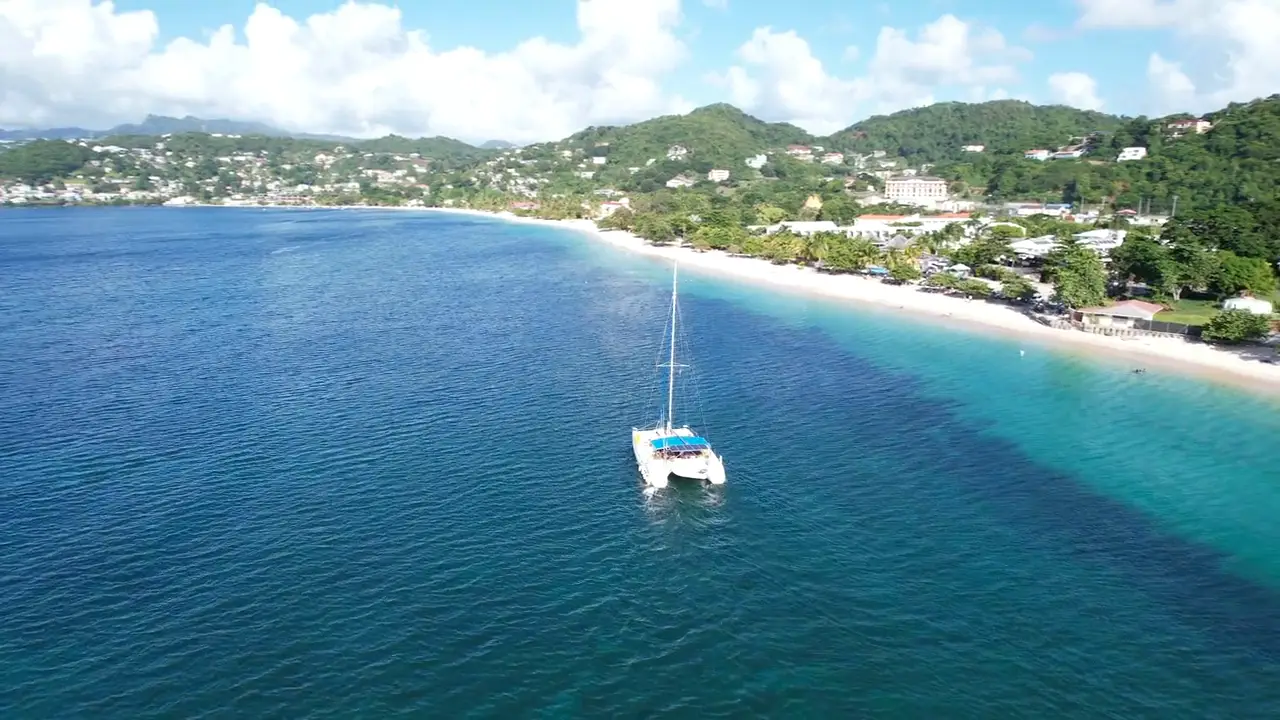 A sailing catamaran yacht at anchor off a long tropical beach