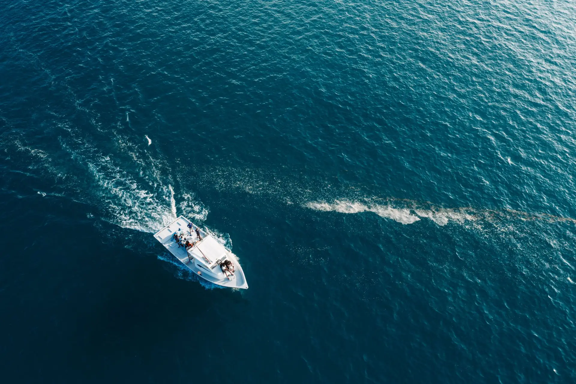 Aerial view of a boat’s wake on bright blue ocean