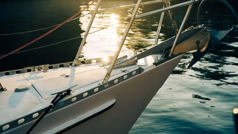 A sailboat bow at sunset on tranquil water