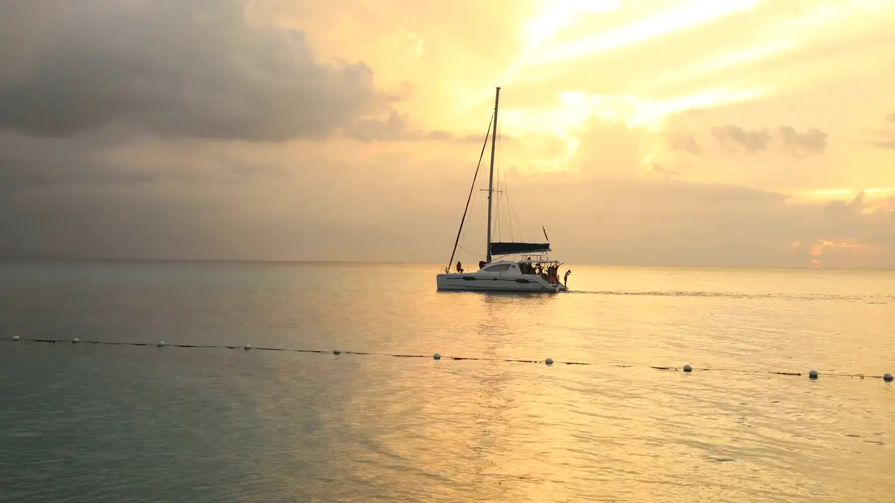 A sailing catamaran yacht at sunset on a tranquil sea